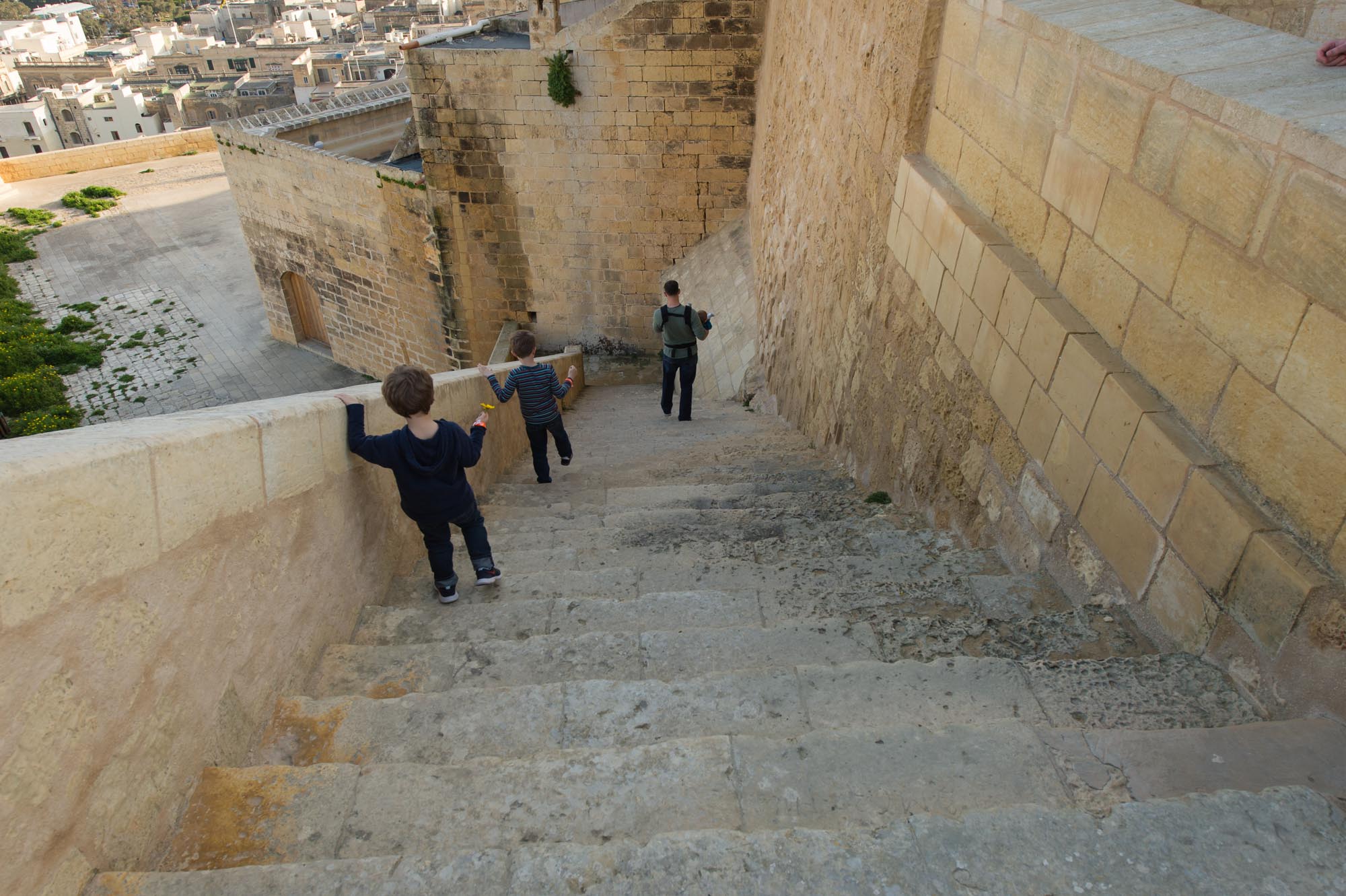 Down the railing, with and towards the subjects.