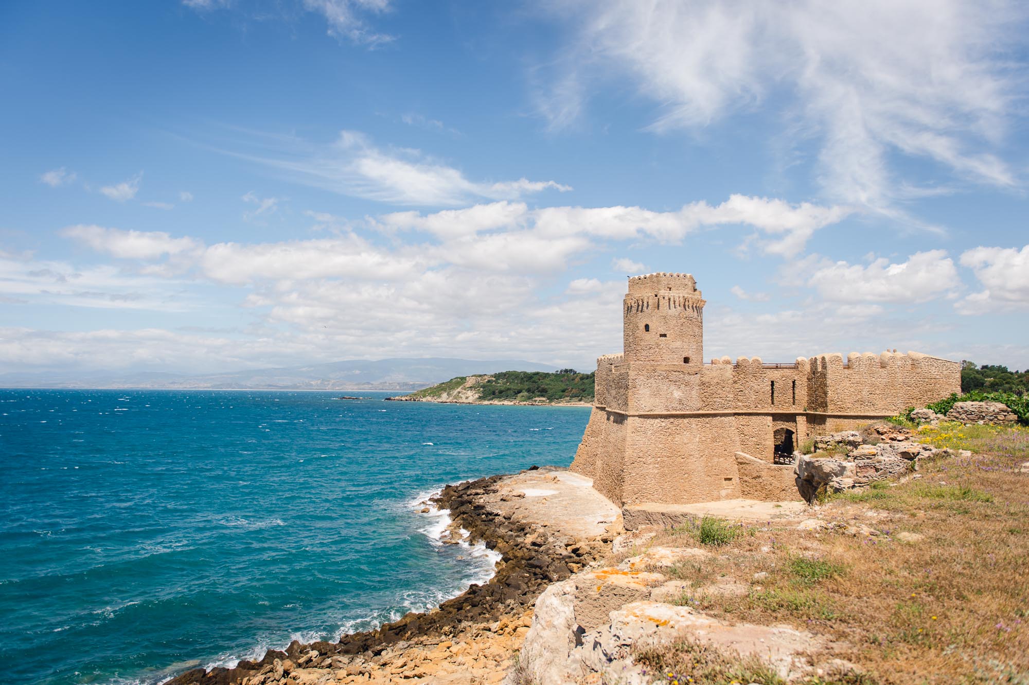 Along both meandering shoreline and horizon towards castle.