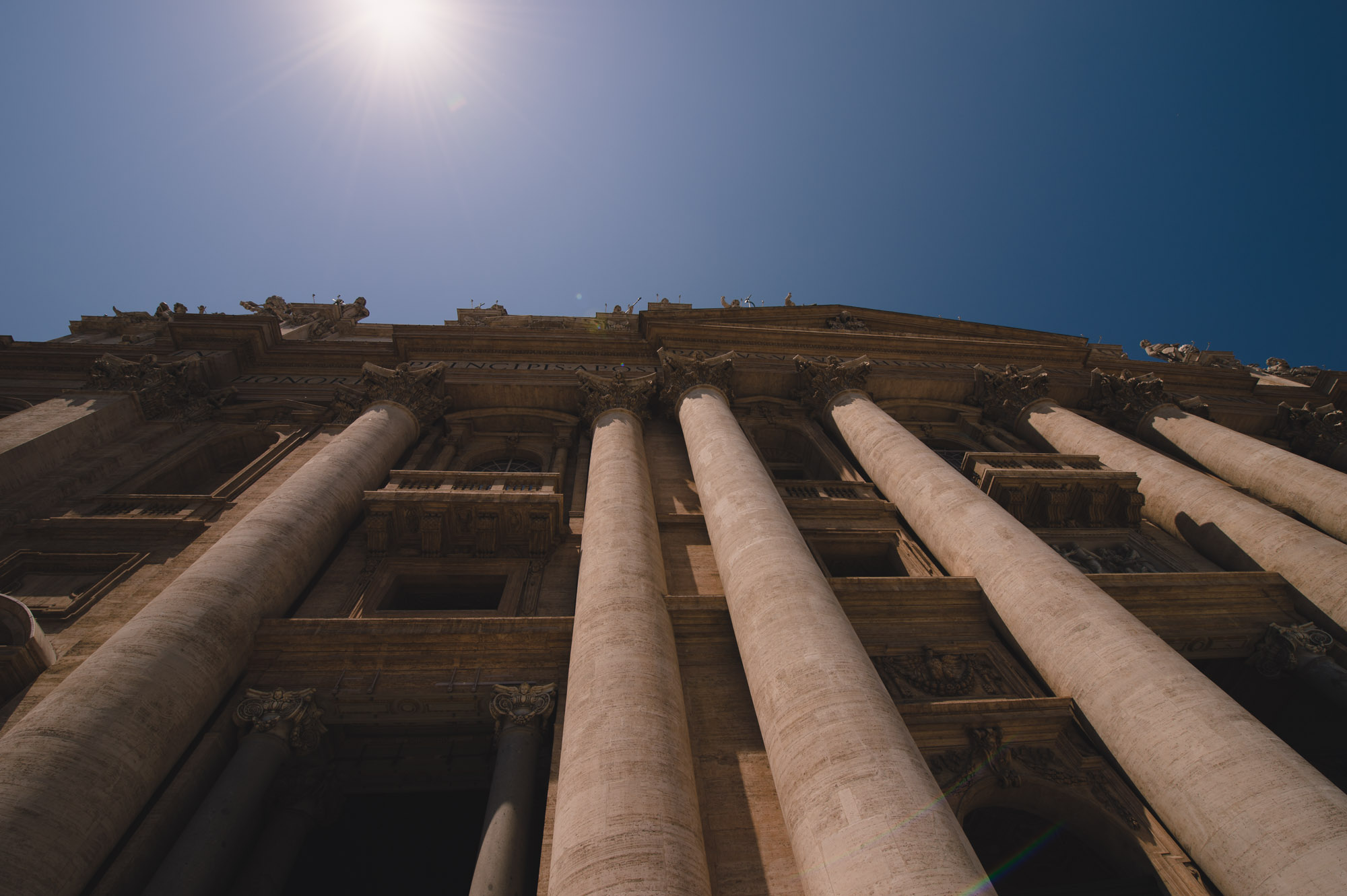 Lines lead up along columns to top of building and the sun.