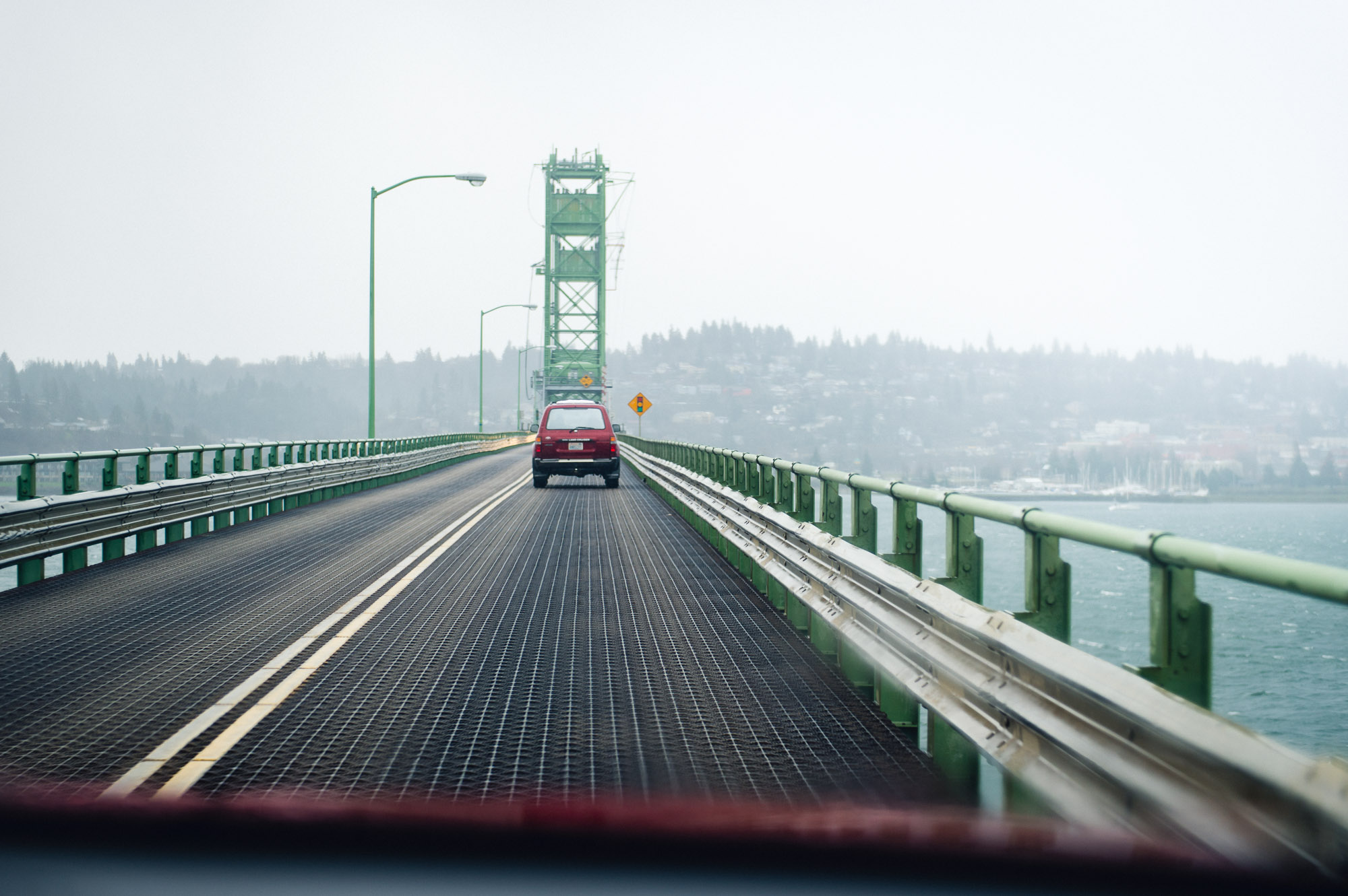 Along railing toward red car and bridge span.