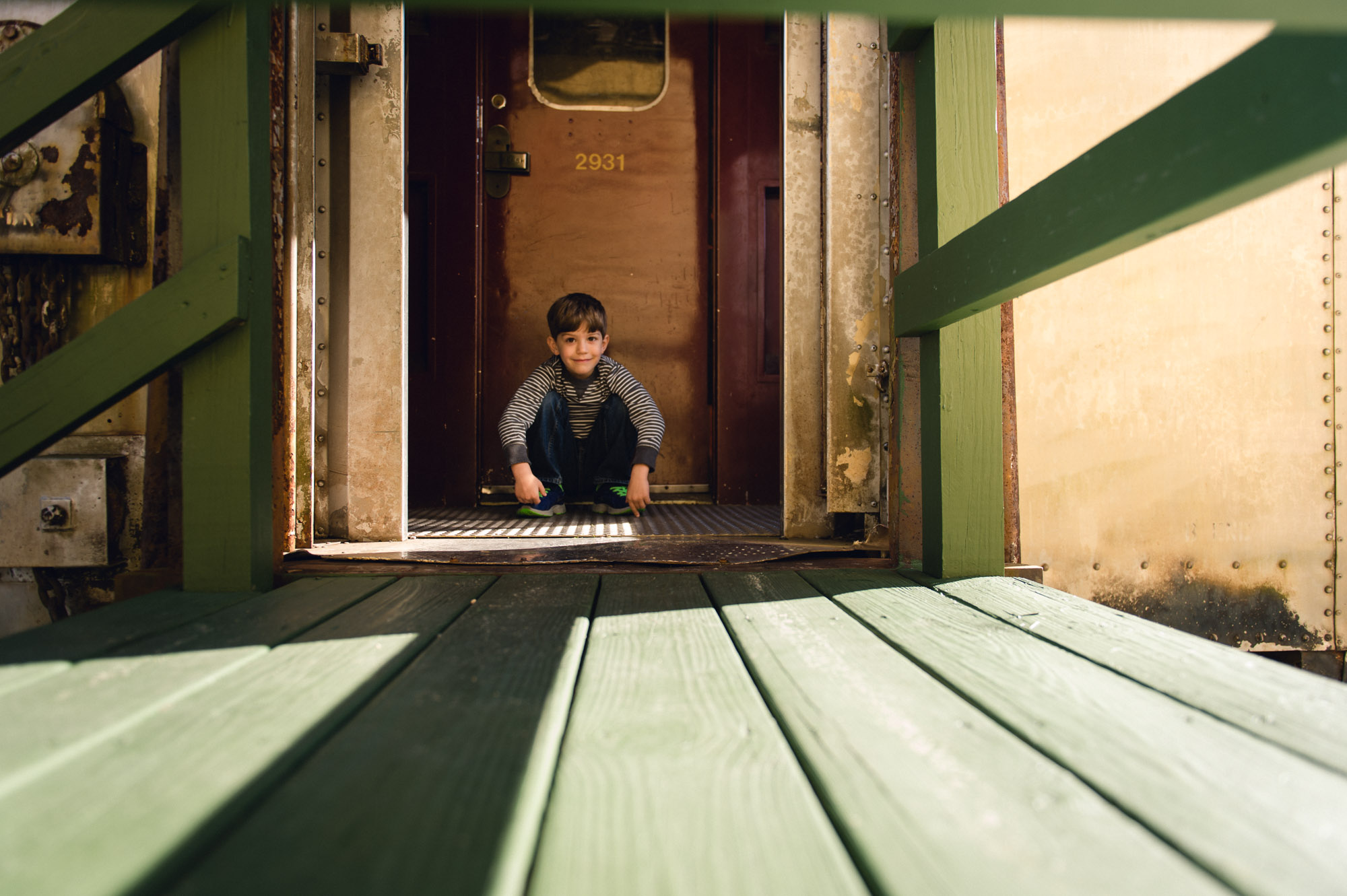 Lines in floor boards and railing lead towards boy.