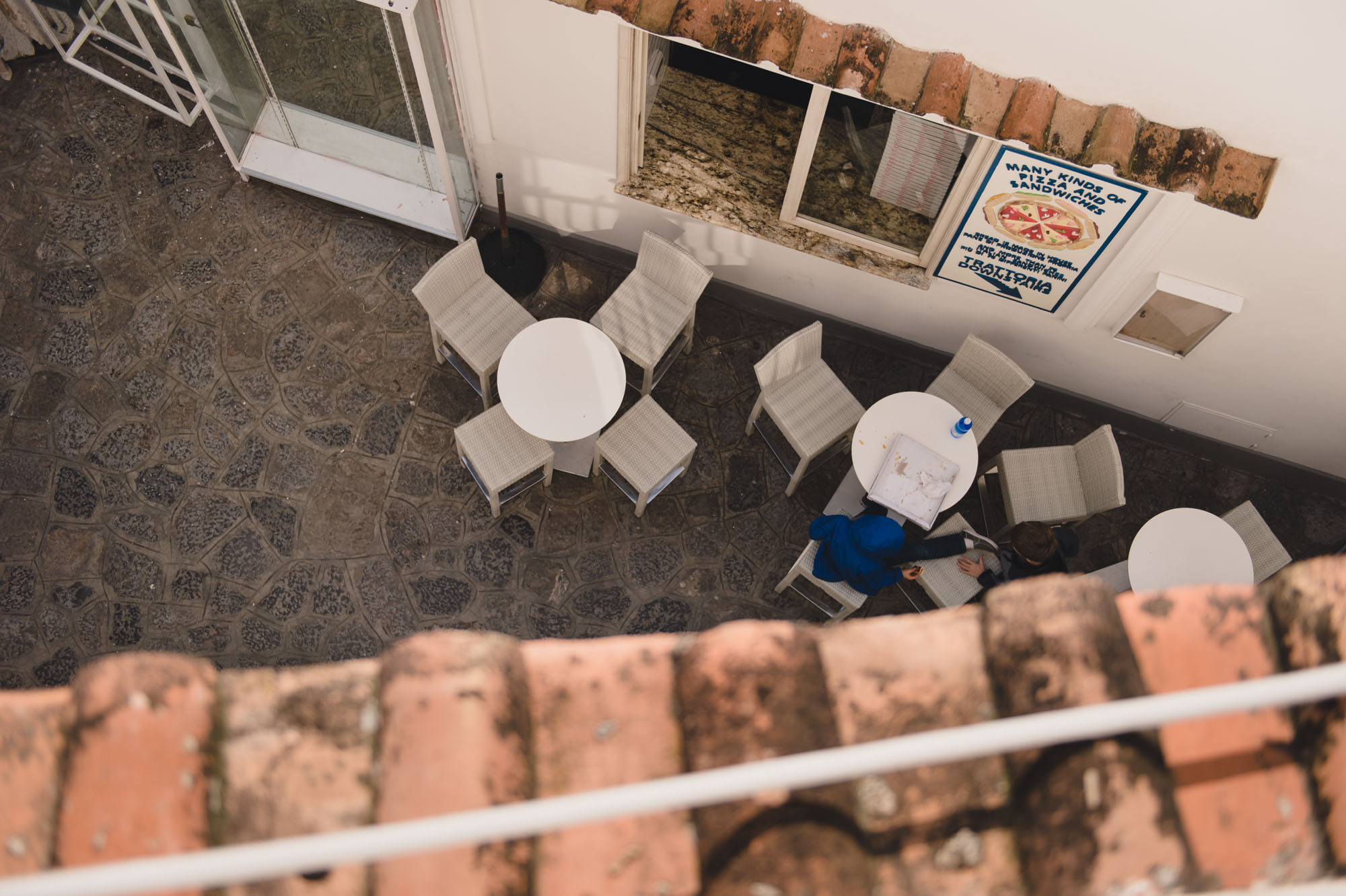 Converging lines of roof and building at the top of the frame meet at the subjects.